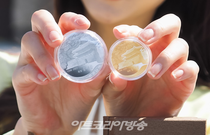 625년의 역사를 지닌 '국보 숭례문'의 기념메달 행사가 8일 오전 서울 중구 세종대로 숭례문 앞에서 진행되었다. 모델이 '국보 숭례문; 기념 메달을 들고 포즈를 취하고 있다. 2023.05.08 사진  ⓒ아트코리아방송 이용선 기자​