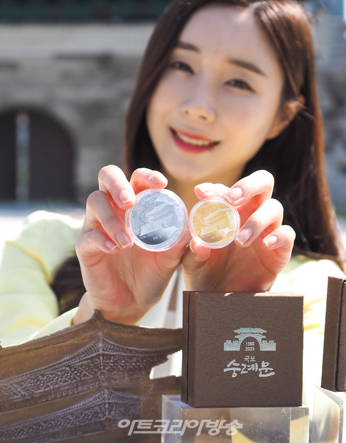 625년의 역사를 지닌 '국보 숭례문'의 기념메달 행사가 8일 오전 서울 중구 세종대로 숭례문 앞에서 진행되었다. 모델이 '국보 숭례문; 기념 메달을 들고 포즈를 취하고 있다. 2023.05.08 사진 ⓒ아트코리아방송 이용선 기자​