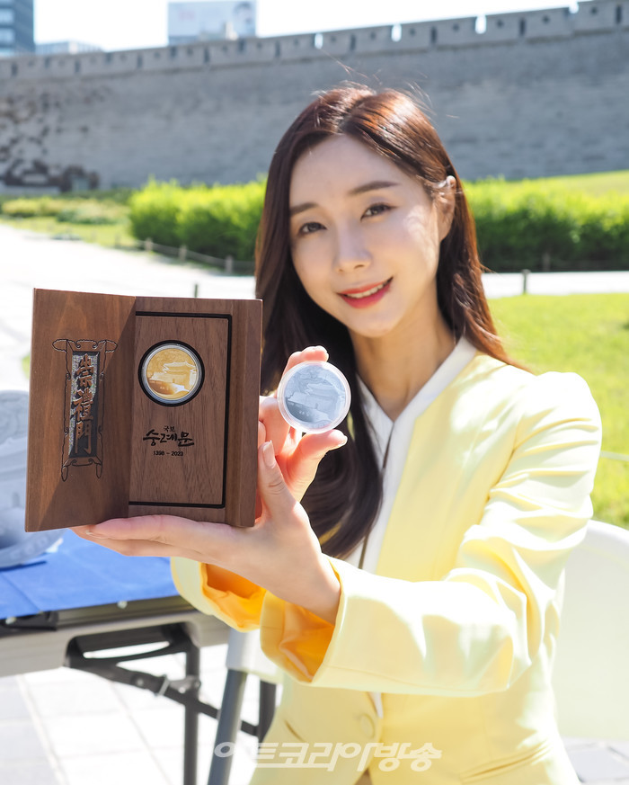 625년의 역사를 지닌 '국보 숭례문'의 기념메달 행사가 8일 오전 서울 중구 세종대로 숭례문 앞에서 진행되었다. 모델이 '국보 숭례문; 기념 메달을 들고 포즈를 취하고 있다. 2023.05.08 사진 ⓒ아트코리아방송 이용선 기자​
