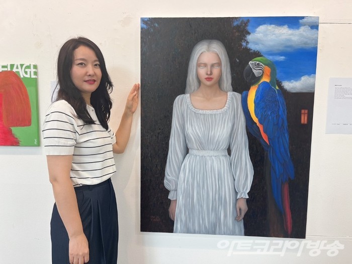 HAA 소속 오지영 작가와 그의 작품, '행복한 왕자 증후군'.  오스카와일드의 '행복한 왕자'의 동화에 빗대어, 인간관계 속에서의 상처를 앵무새에게 자신의 색을 빼앗긴 소녀로 표현하였다.  