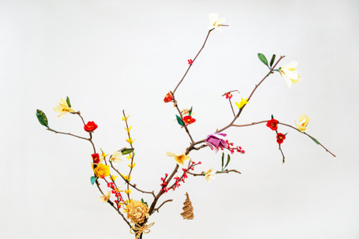  풀짚공예문화예술동호회원들의 공동 작품으로 건조된 옥수수껍질을 다리고 오려 묶어 매화, 장미, 목련, 개나리 등 좋아하는 꽃들을 만들어 가지치기로 버려진 목련나무 가지 위에 장식했다