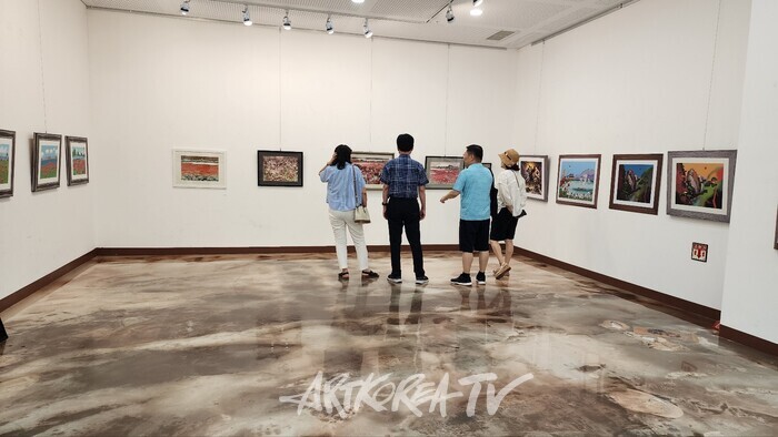 황토회 회원들이 출품한 수채화 앞에서 작품 감상하는 관람객들​